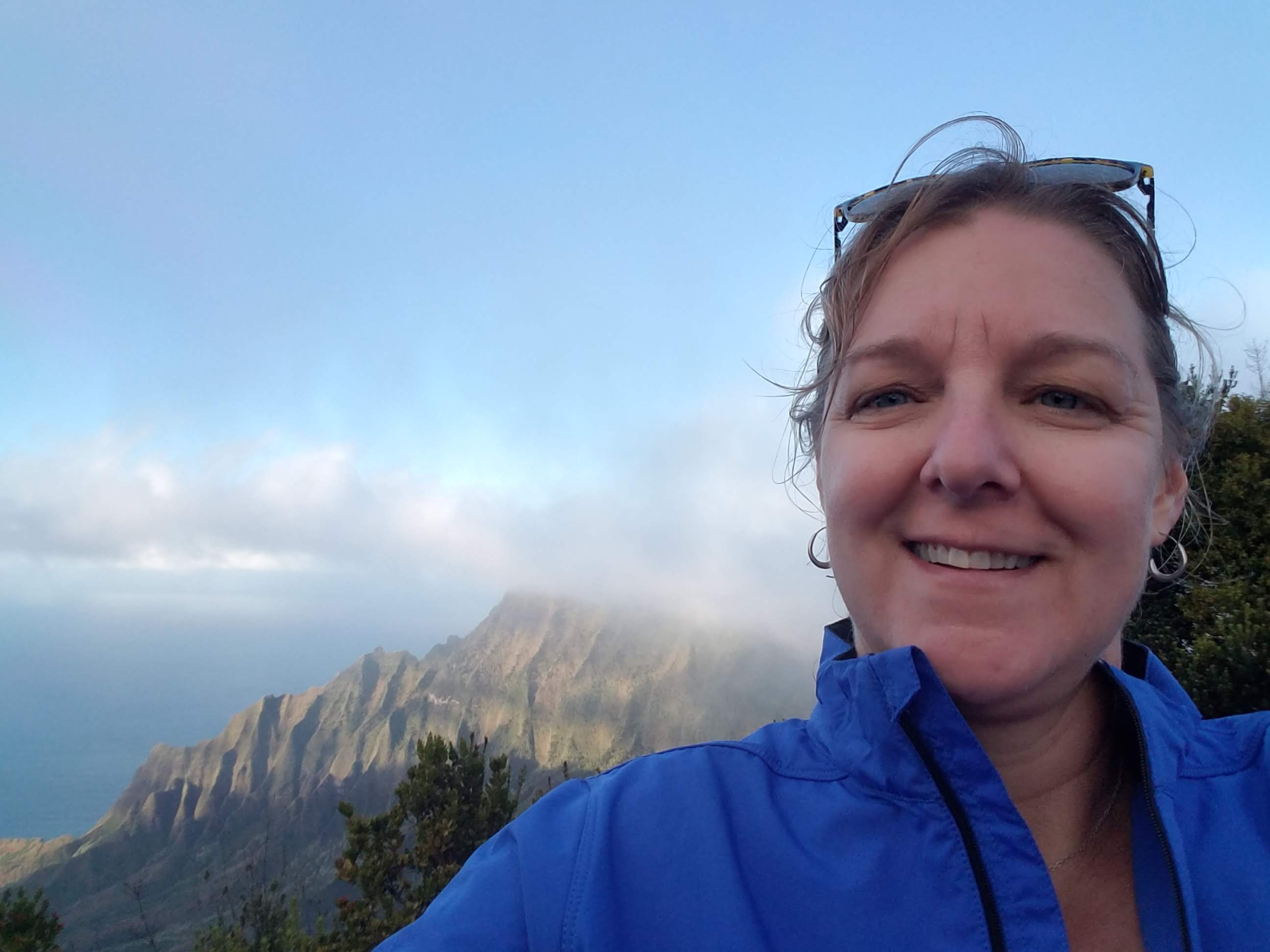 WWU Outstanding Grad Theressa Porcarelli Carey smiling with mountainside and clouds in the background