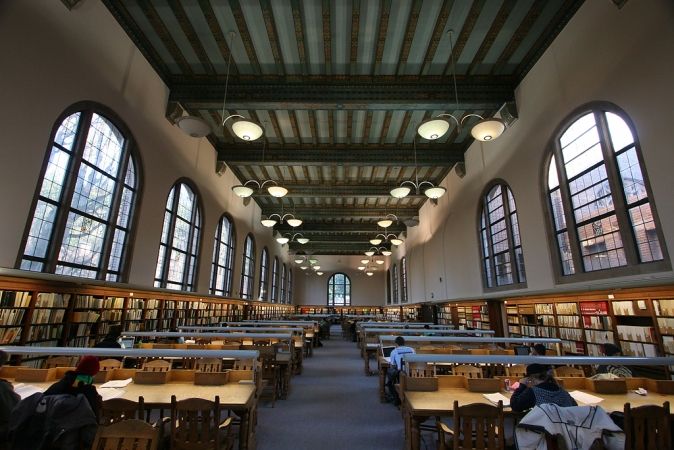 library reading room, with high ornate ceiling, tall windows, wooden tables
