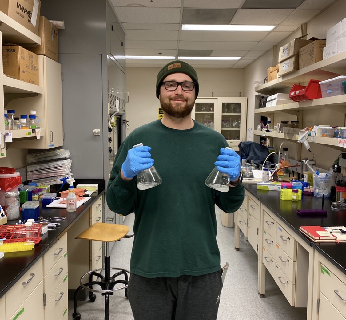 WWU graduate Tanner Thuet-Davenport in the lab holding two beakers