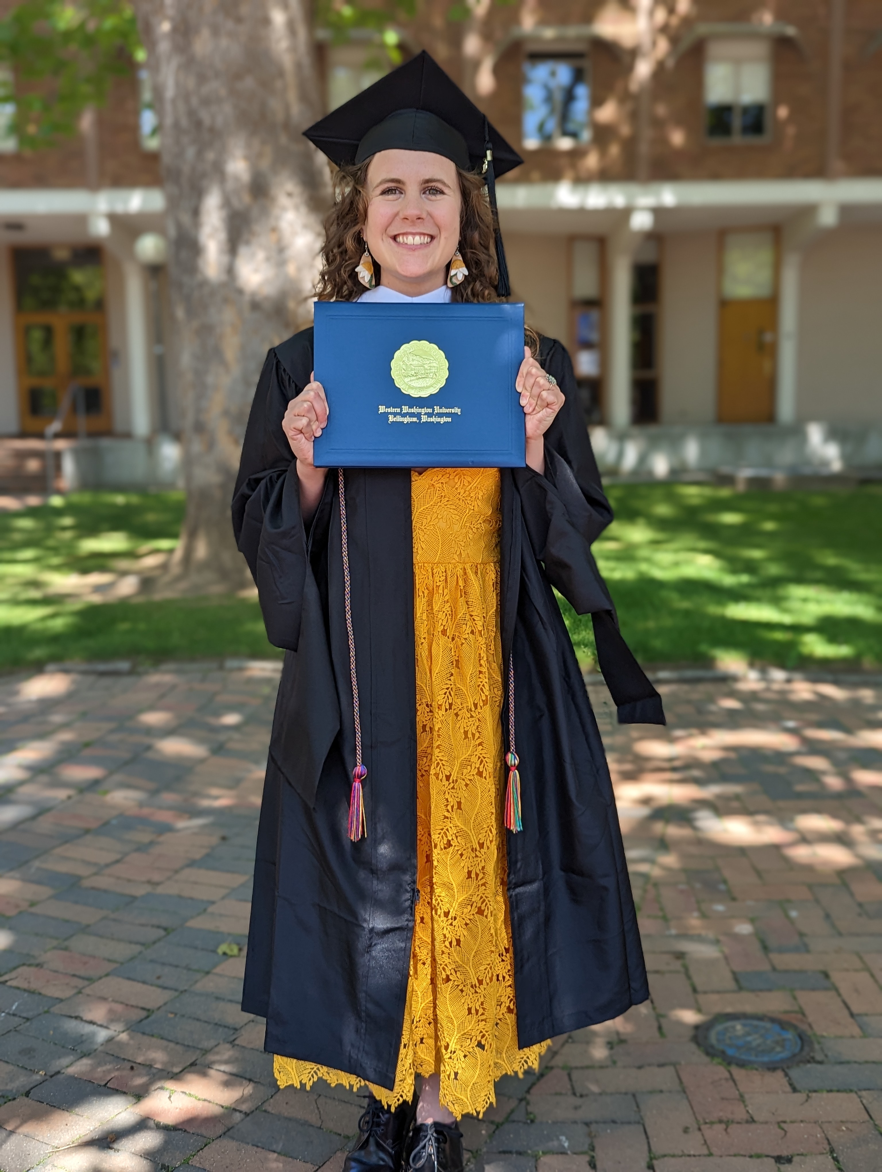 WWU Outstanding Grad Student Sophia Brauner smiling in hood, cap, and gown