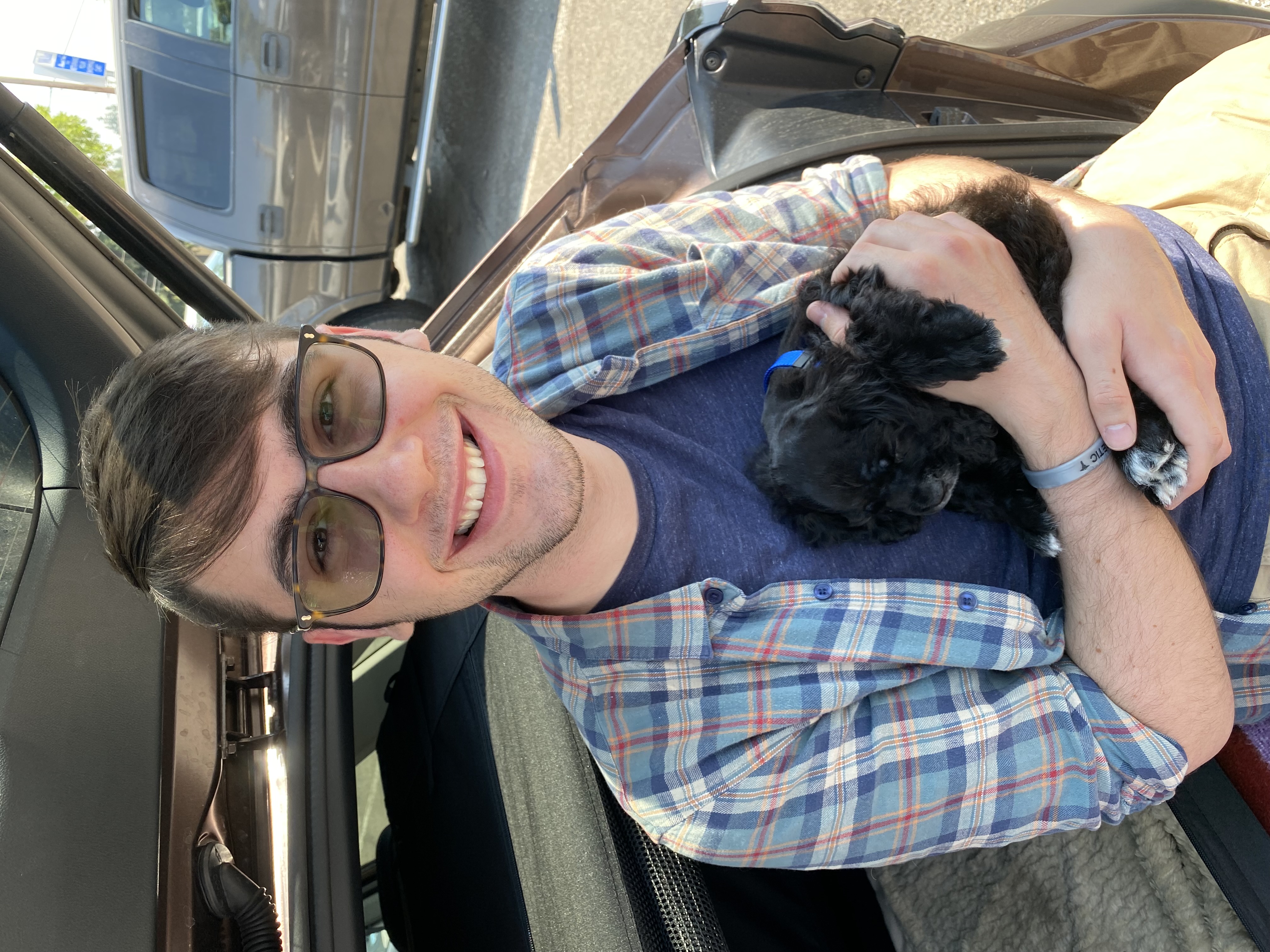 WWU Outstanding Grad Student Hunter Stuehm smiling and holding a small puppy