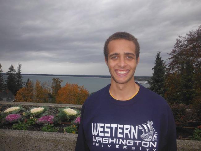 WWU graduate student Maxx Antush with plants and a large body of water in the background