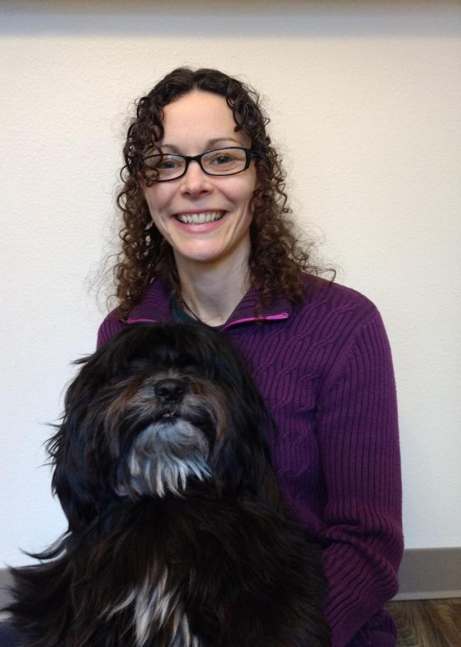 WWU graduate student Rachael Jacobus smiling with large, shaggy, black dog in front of a white background