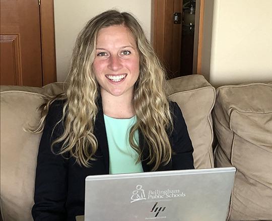 WWU graduate student Jessica Wallace smiling, sitting on a couch with a laptop in her lap