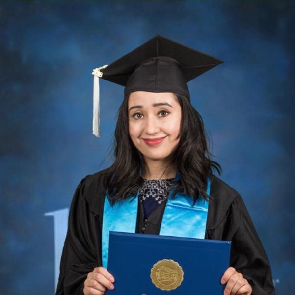 WWU graduate Tessa Borrego in cap, gown, and hood with blue background